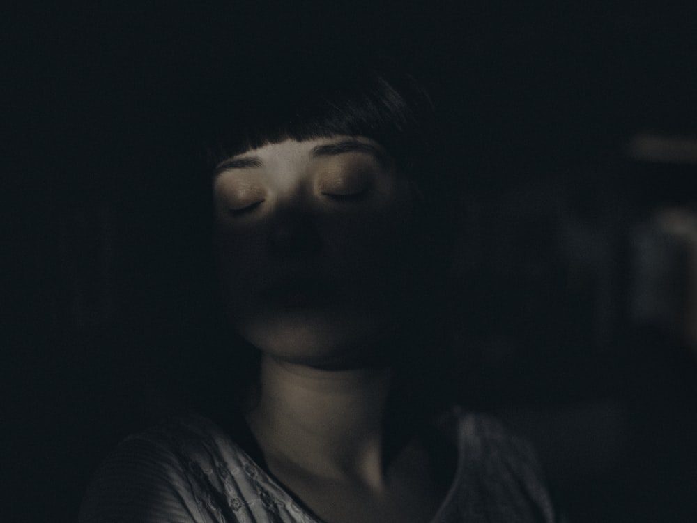 Woman in a quiet dark room in a moment of stillness and introspection during deep therapy work