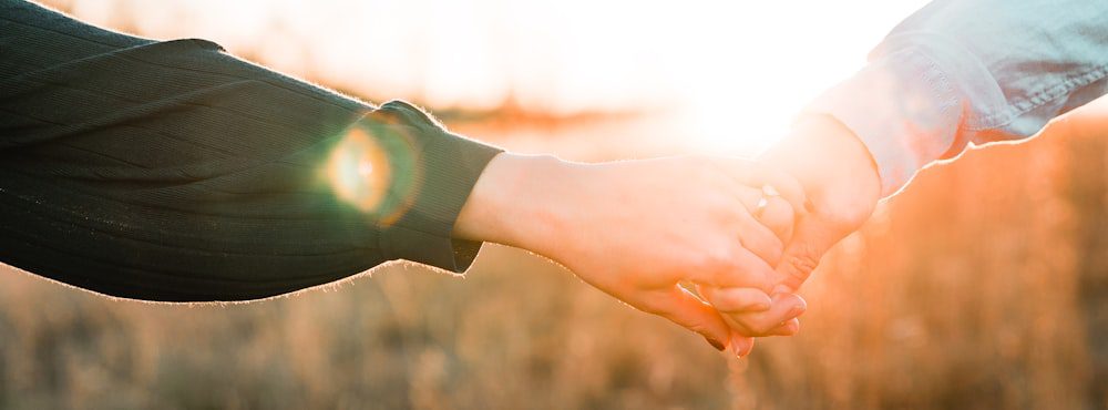 Two hands reaching toward each other in golden light, feeling not alone in AEDP therapy