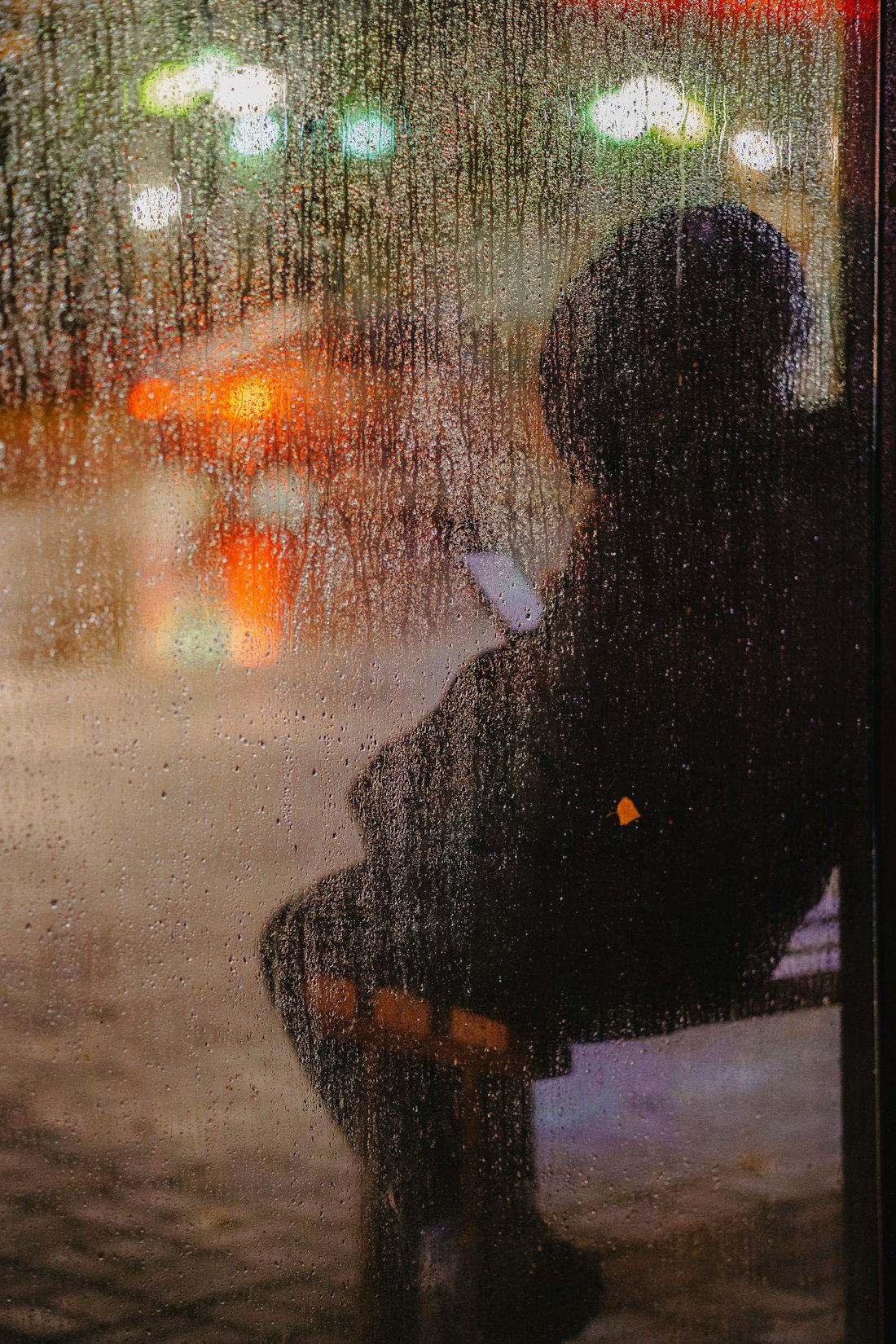 Person sitting by a rain-streaked window at dusk, reflecting during EMDR therapy