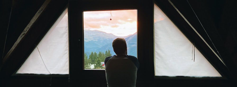 Person looking out a window toward mountains, the slower, deeper pace of psychodynamic therapy