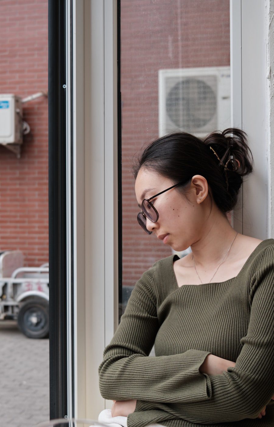 Asian woman resting by a window, trauma therapy for Chinese and Asian American adults