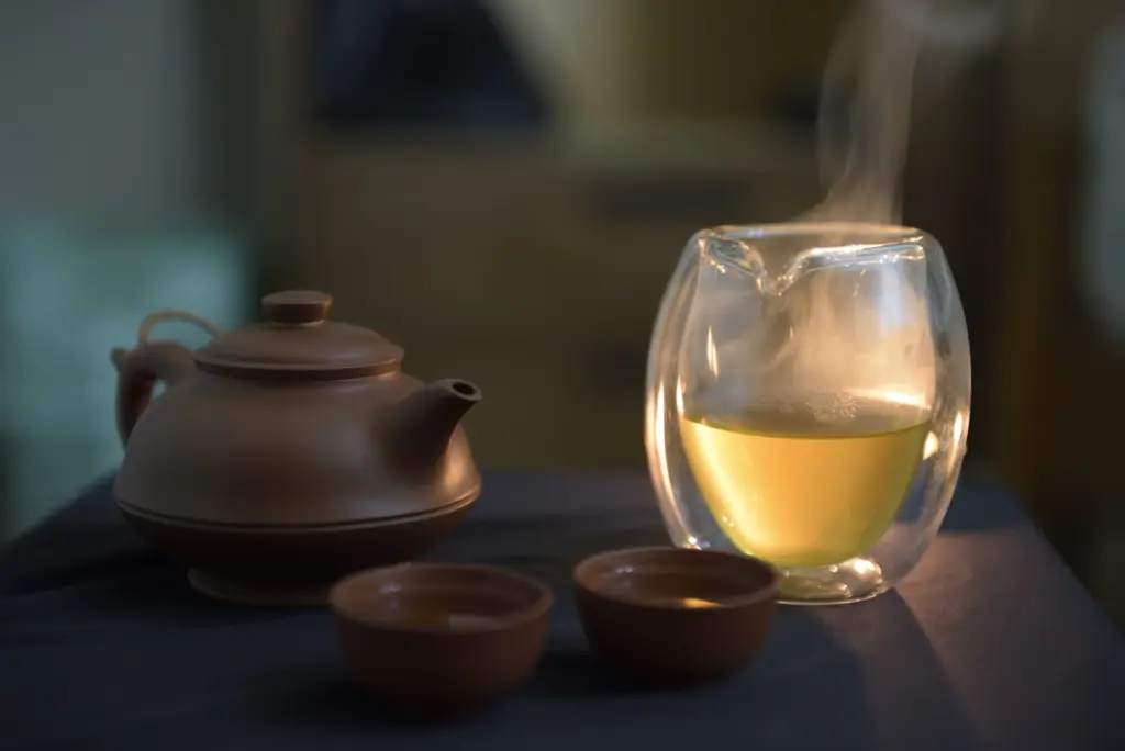 A clay teapot and glass of tea glowing in warm light