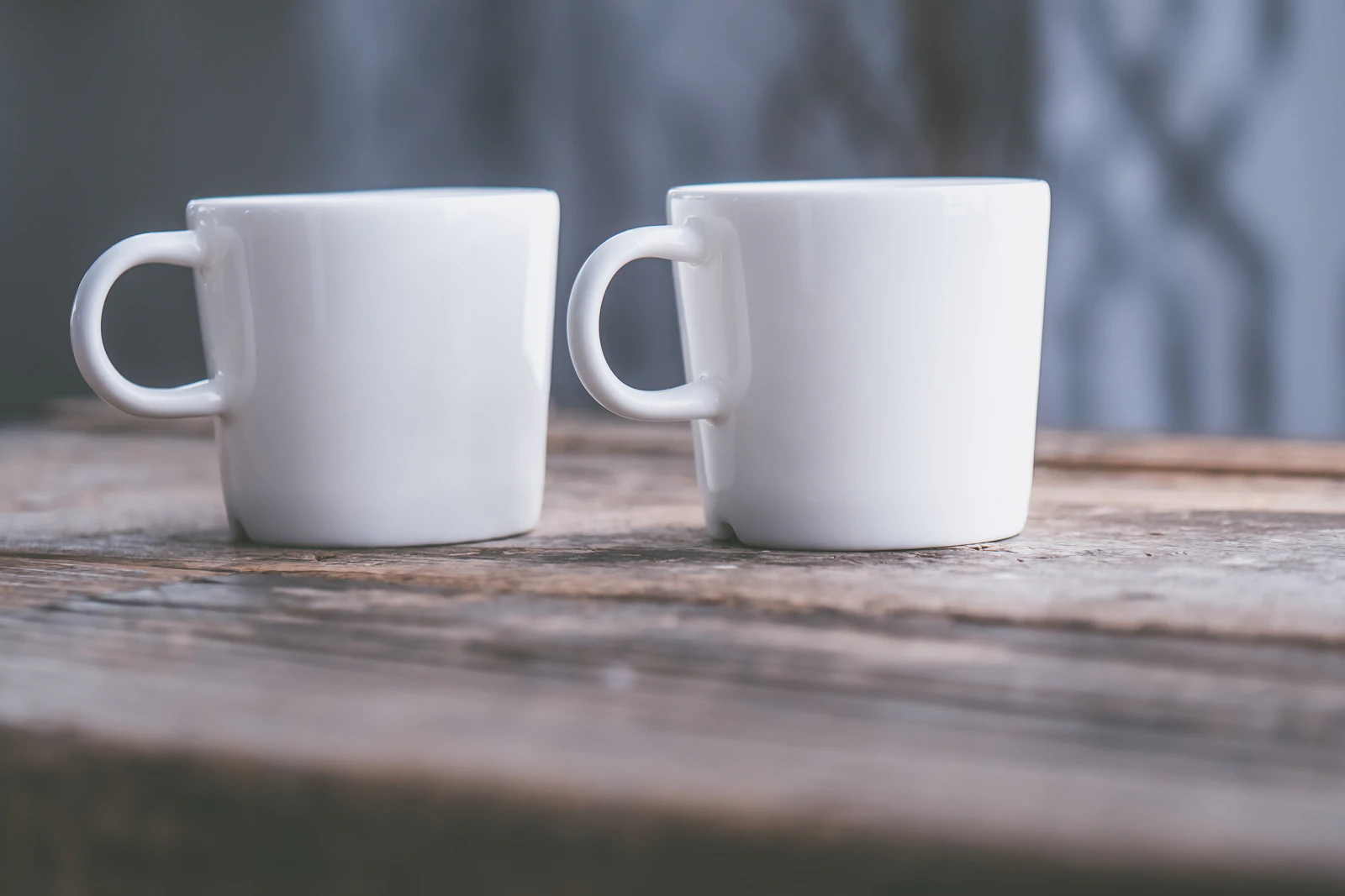 Two white mugs side by side on a wooden table