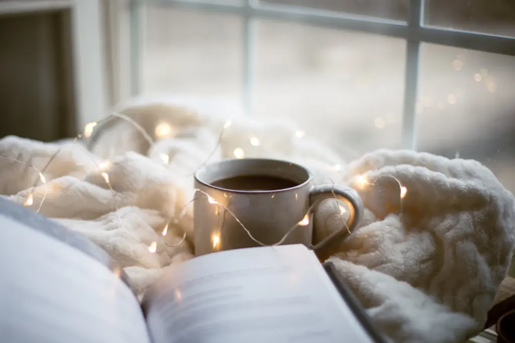 A cup of tea and an open book on a soft blanket