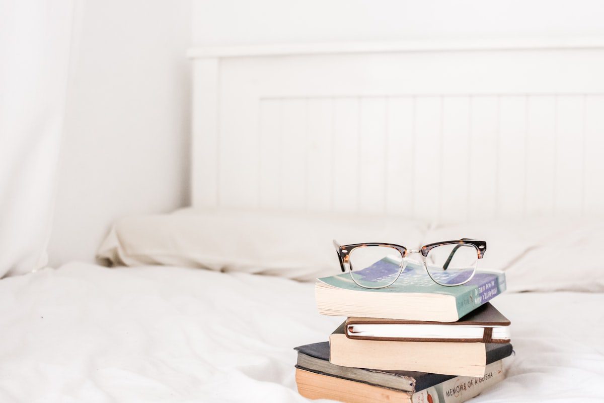 A stack of books with reading glasses resting on top