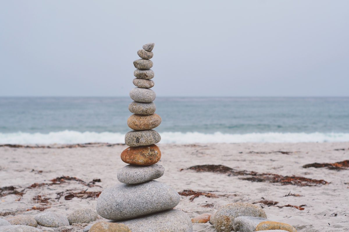 A stack of balanced stones on a pale beach