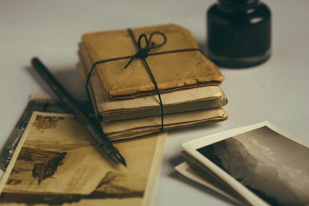 A stack of old letters tied with string beside a fountain pen